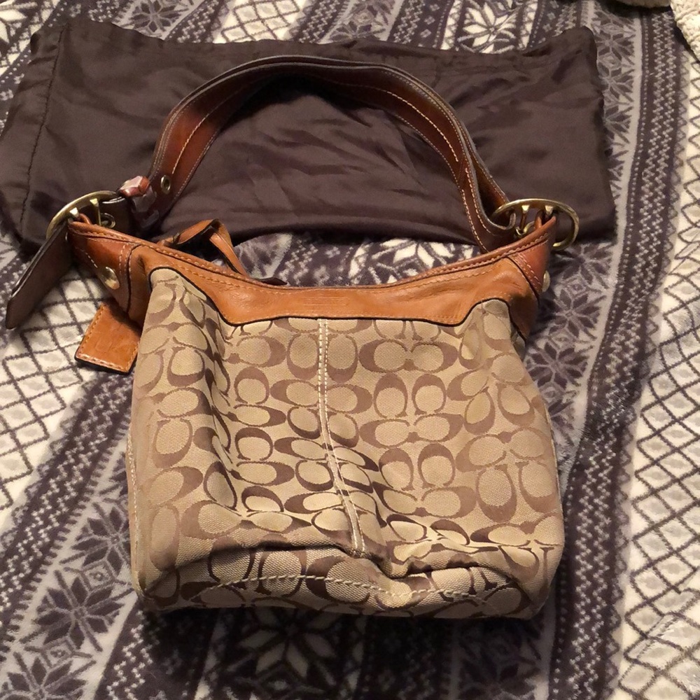 A Coach bag with leather trim and handles, it’s a bucket style purse